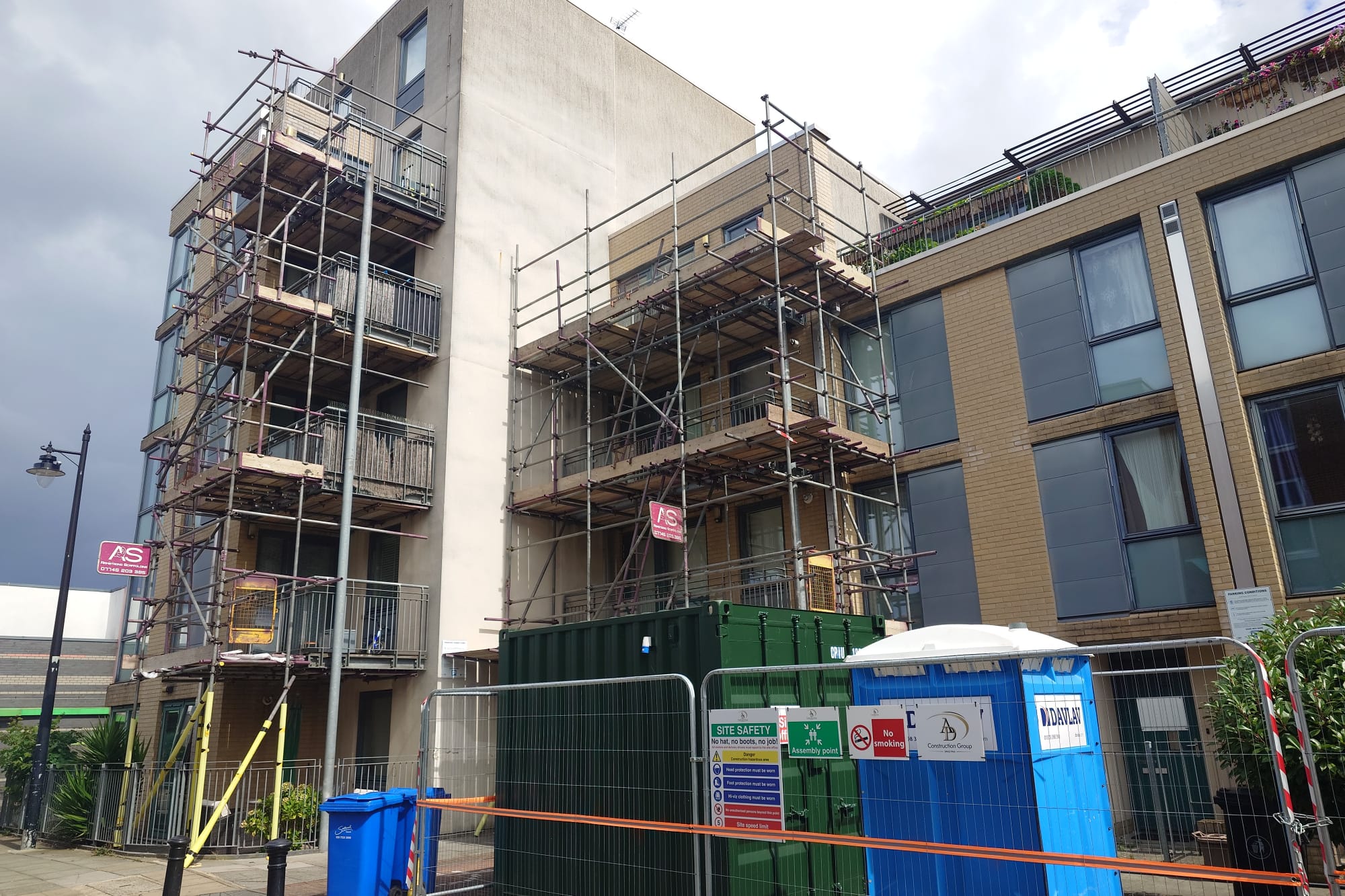 Armstrong Scaffolding safe access scaffold with cantilevered balcony platforms and timber working lifts erected to a multi-storey residential apartment block for balcony repair and external refurbishment works, with site safety hoarding and welfare in place
