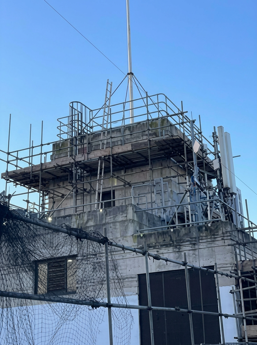 Armstrong Scaffolding top-lift new build scaffold with edge protection and tower crane above a multi-storey residential development in London under a clear blue sky