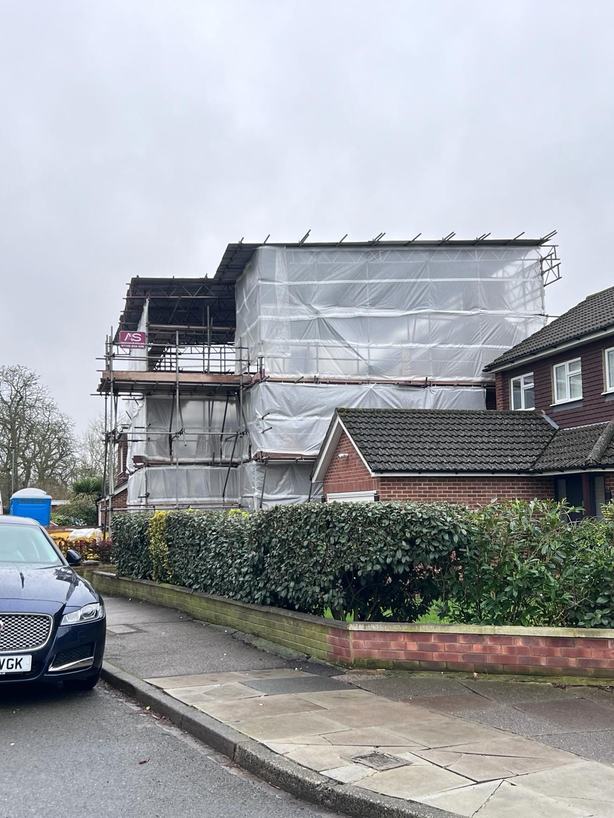 Armstrong Scaffolding temporary roof installation on a residential loft conversion in London, multi-lift independent scaffold with branded AS banner and full white sheeted weather protection viewed from street level