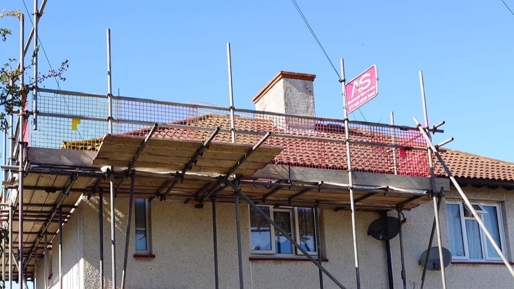 Eaves level working lift with double guardrail, mesh brickguards and debris netting below the roof line