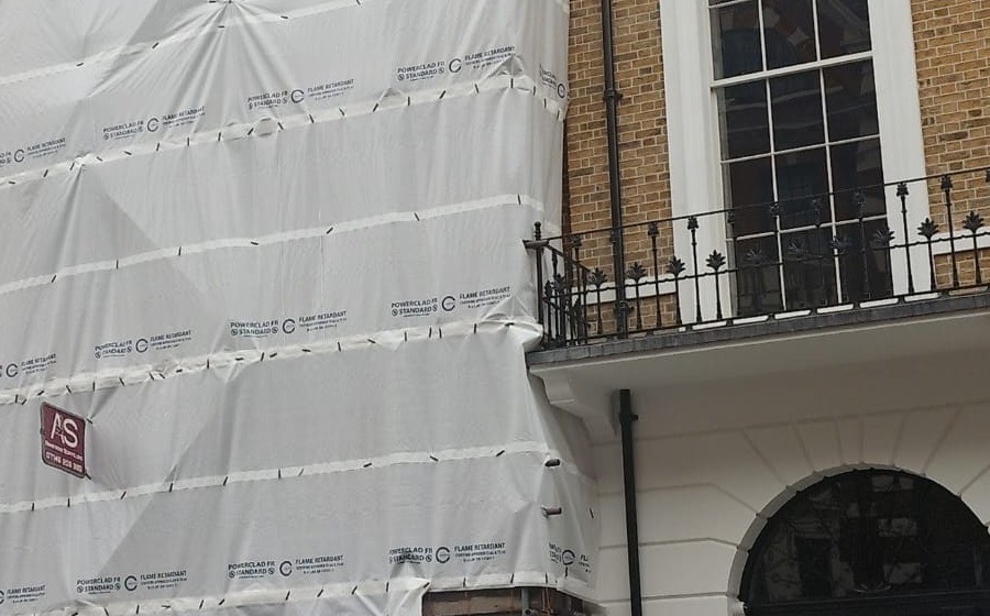 Close view of the scaffold sheeting showing the flame retardant approval marking printed across the material