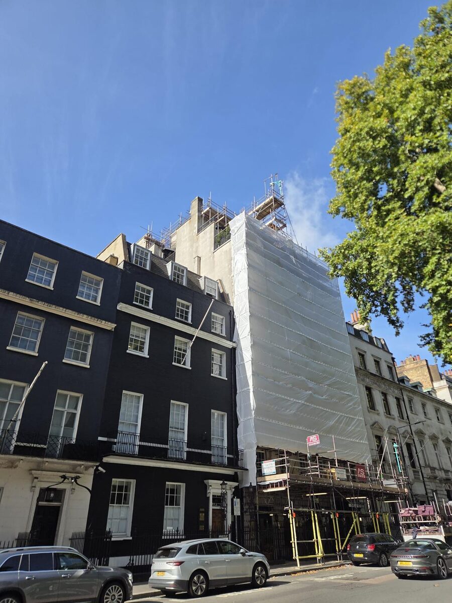 The finished shrink wrapped Armstrong Scaffolding structure on Berkeley Square, seen along the street between a black painted Georgian terrace and a stucco fronted building
