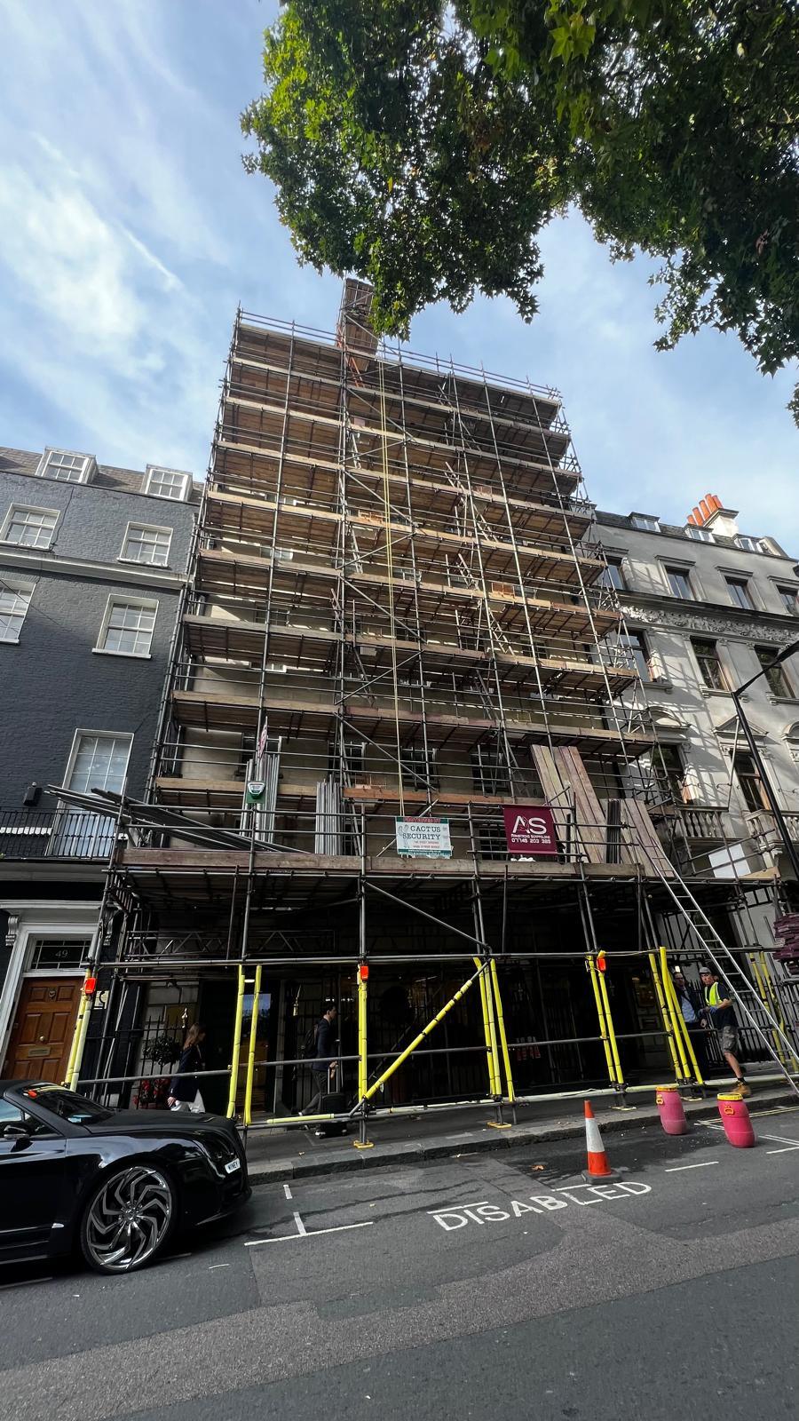 Armstrong Scaffolding designed scaffold structure rising the full height of a period terrace on Berkeley Square, Mayfair, with a boarded pedestrian gantry over the footway