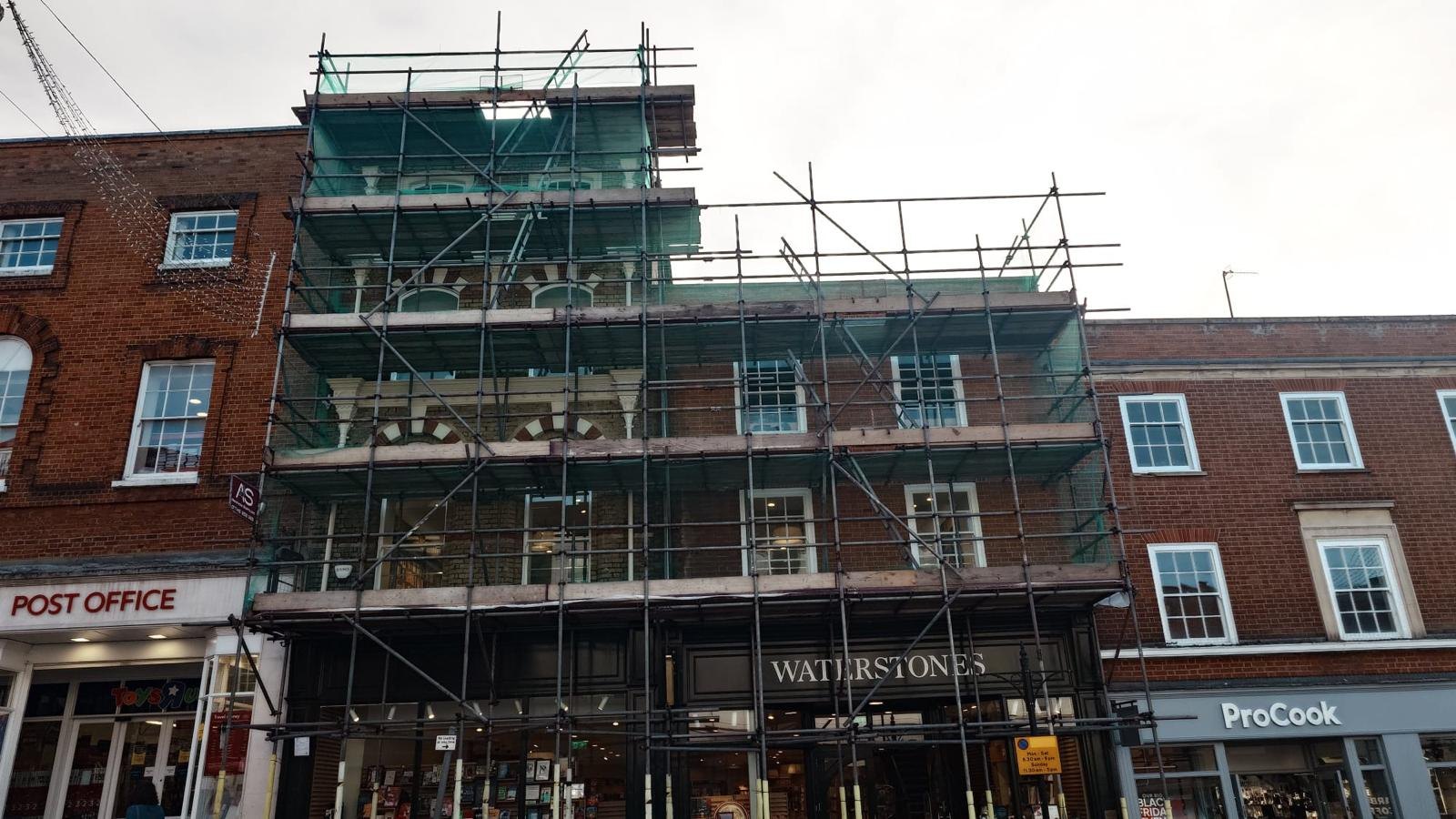 Armstrong Scaffolding full height façade scaffold with debris netting above the Waterstones shopfront on Guildford High Street